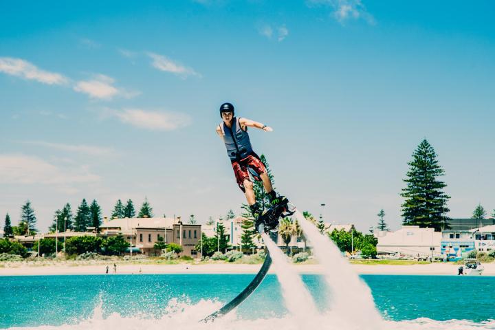 a man flying through the air while swimming in a body of water